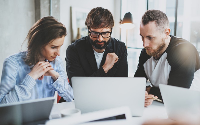 Group of IT leaders reading report about business strategy on laptop computer