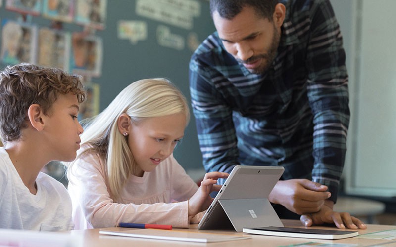 Teacher uses Surface device to teach two students in classroom