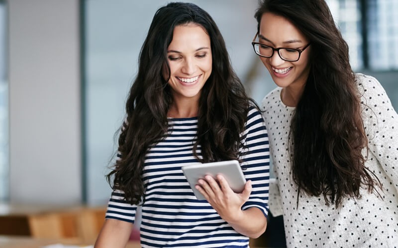 Two women smiling looking at tablet