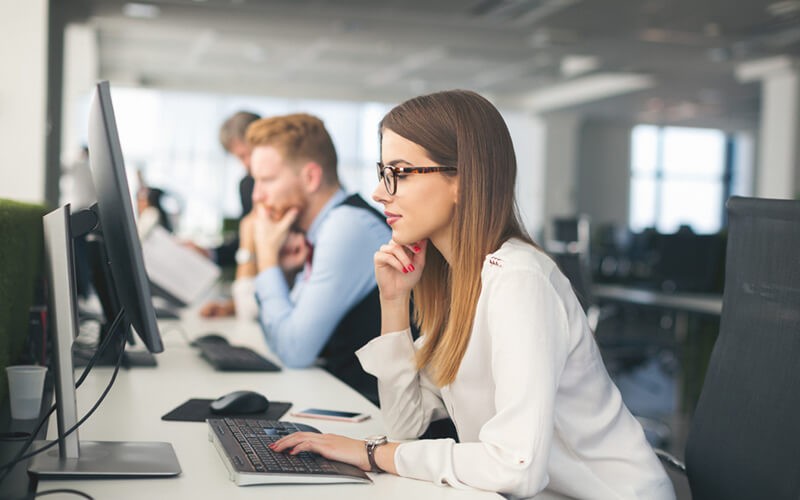 Business woman on desktop computer reviewing expenditures