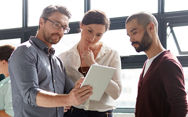 Business professionals gathered around tablet reading IDG Cloud research study