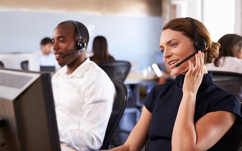 IT support experts on headsets wait to take calls in Remote Network Operations Center