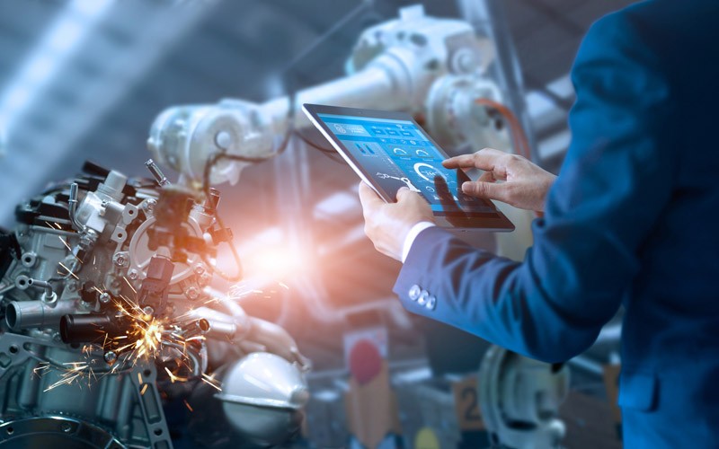Business professional using tablet to monitor manufacturing