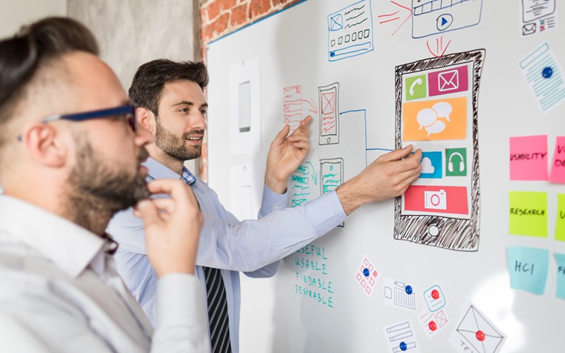 UX designers brainstorm ideas with wireframes and sticky notes