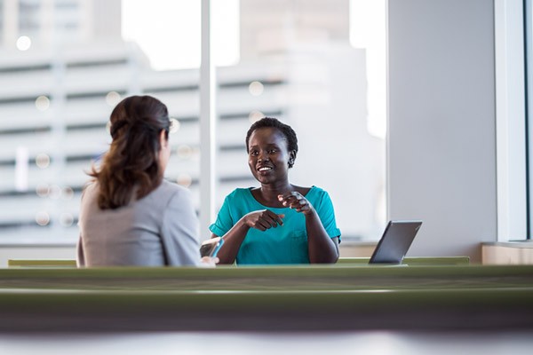 Two business woman discuss technology leasing and financing at table