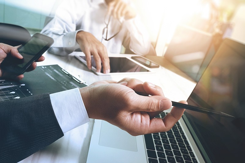 Business professionals have meeting while using multiple mobile devices